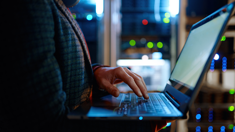 Close up of person holding an open laptop.
