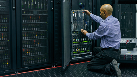 Man kneeling in front of a server stack.